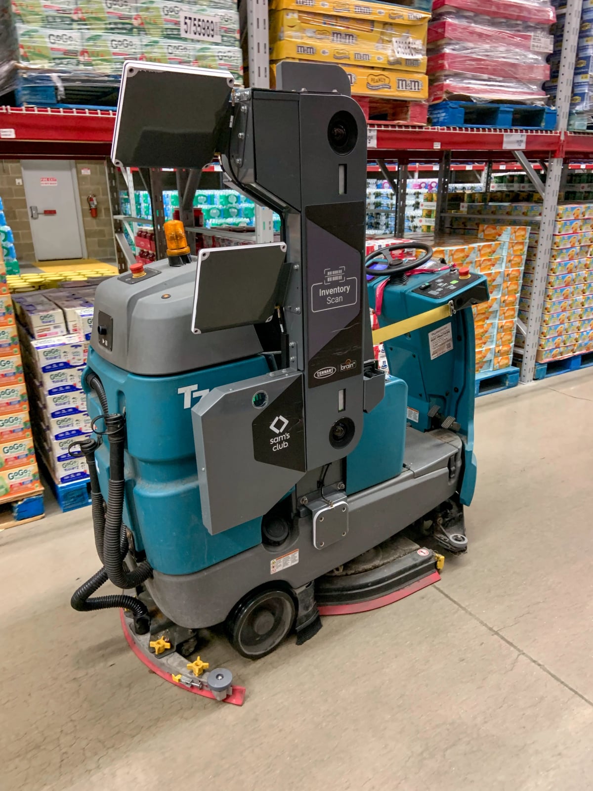 A commercial autonomous floor scrubber parked in a warehouse retail aisle